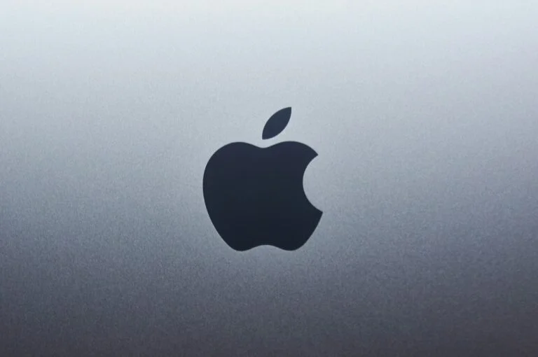 A dark apple logo centered on a smooth grey metallic surface