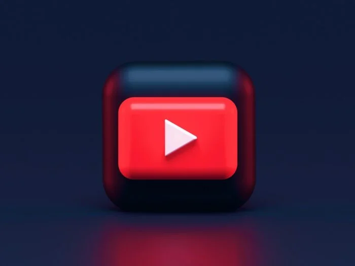 A 3D red play button icon on a dark blue background
